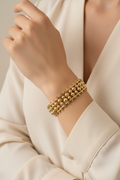 Gold bracelet on a person's wrist with a neutral background