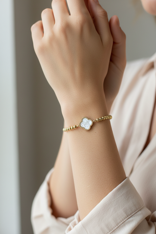 Close-up of a hand wearing a gold bracelet with a decorative clasp.