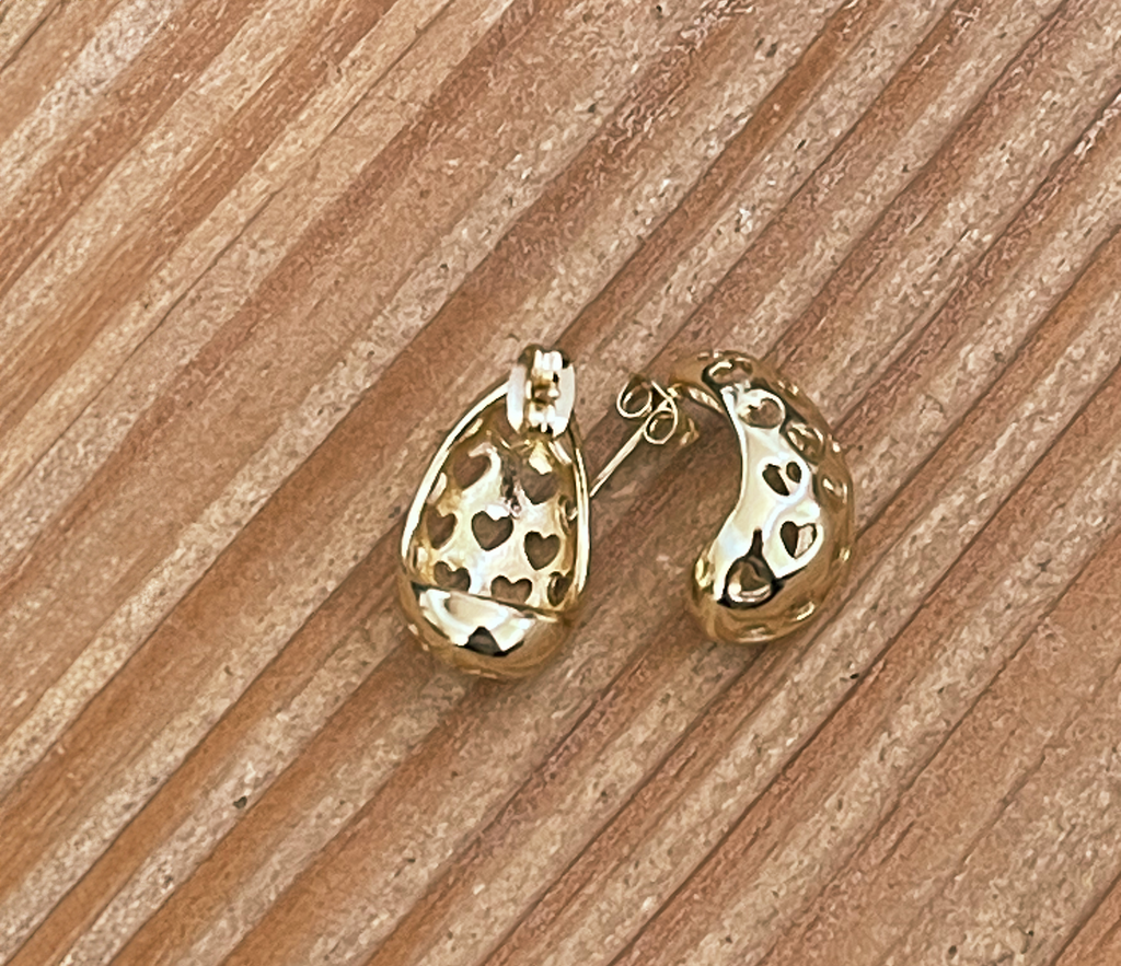 Gold earrings on a wooden surface