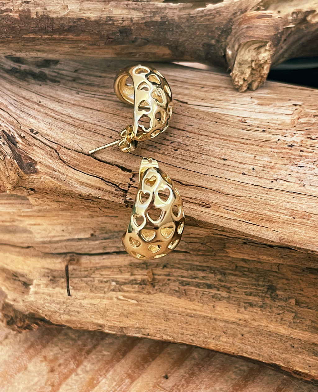 Gold earrings on a wooden surface