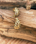 Gold earrings on a wooden surface