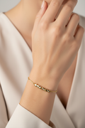 Gold bracelet on a person's wrist with a neutral background
