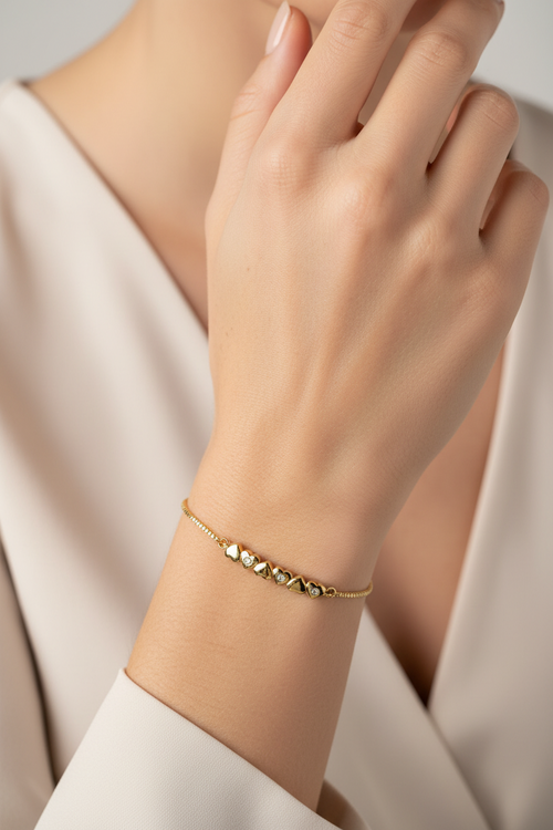 Gold bracelet on a person's wrist with a neutral background