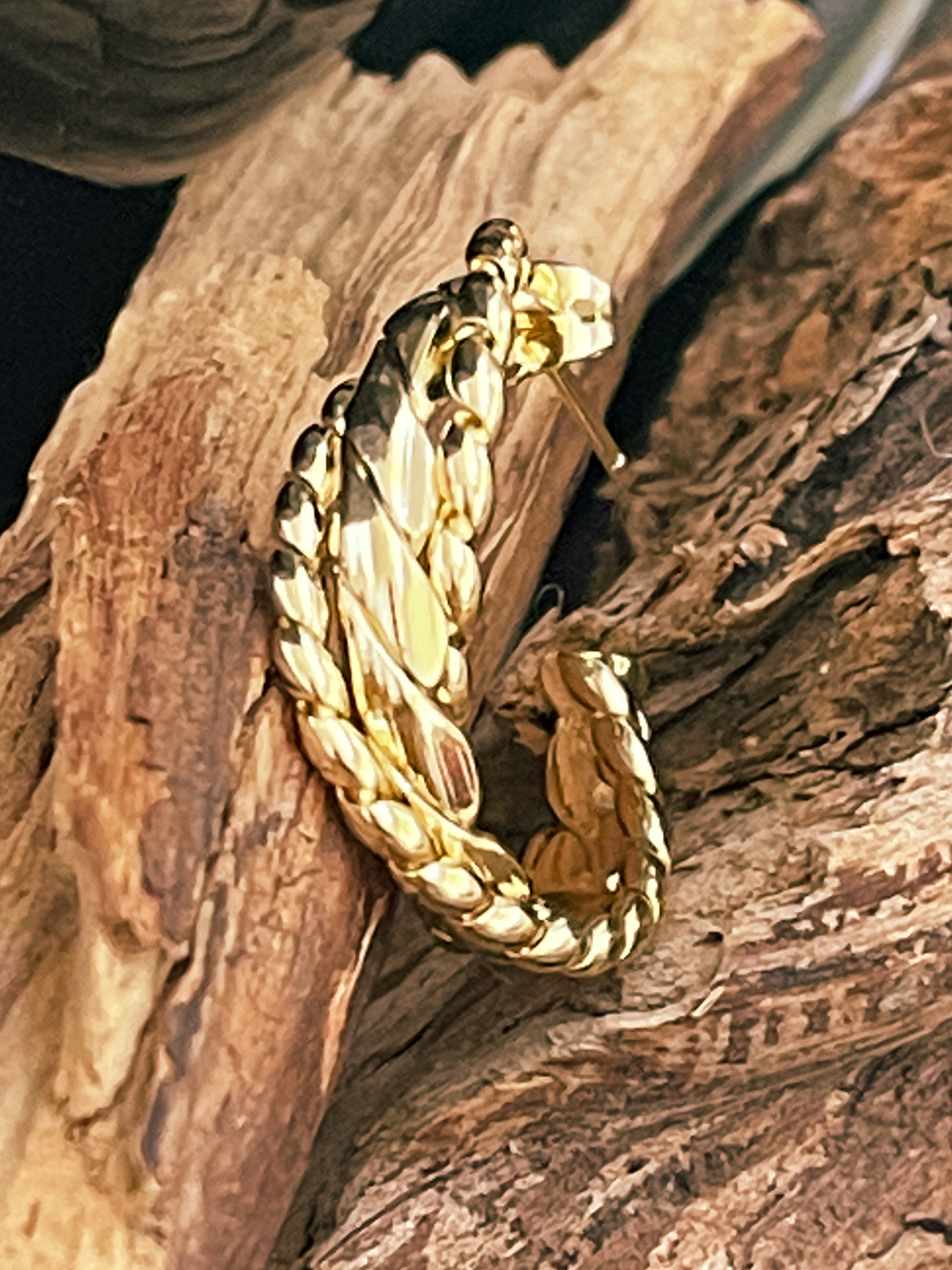 Gold hoop earring on a piece of wood