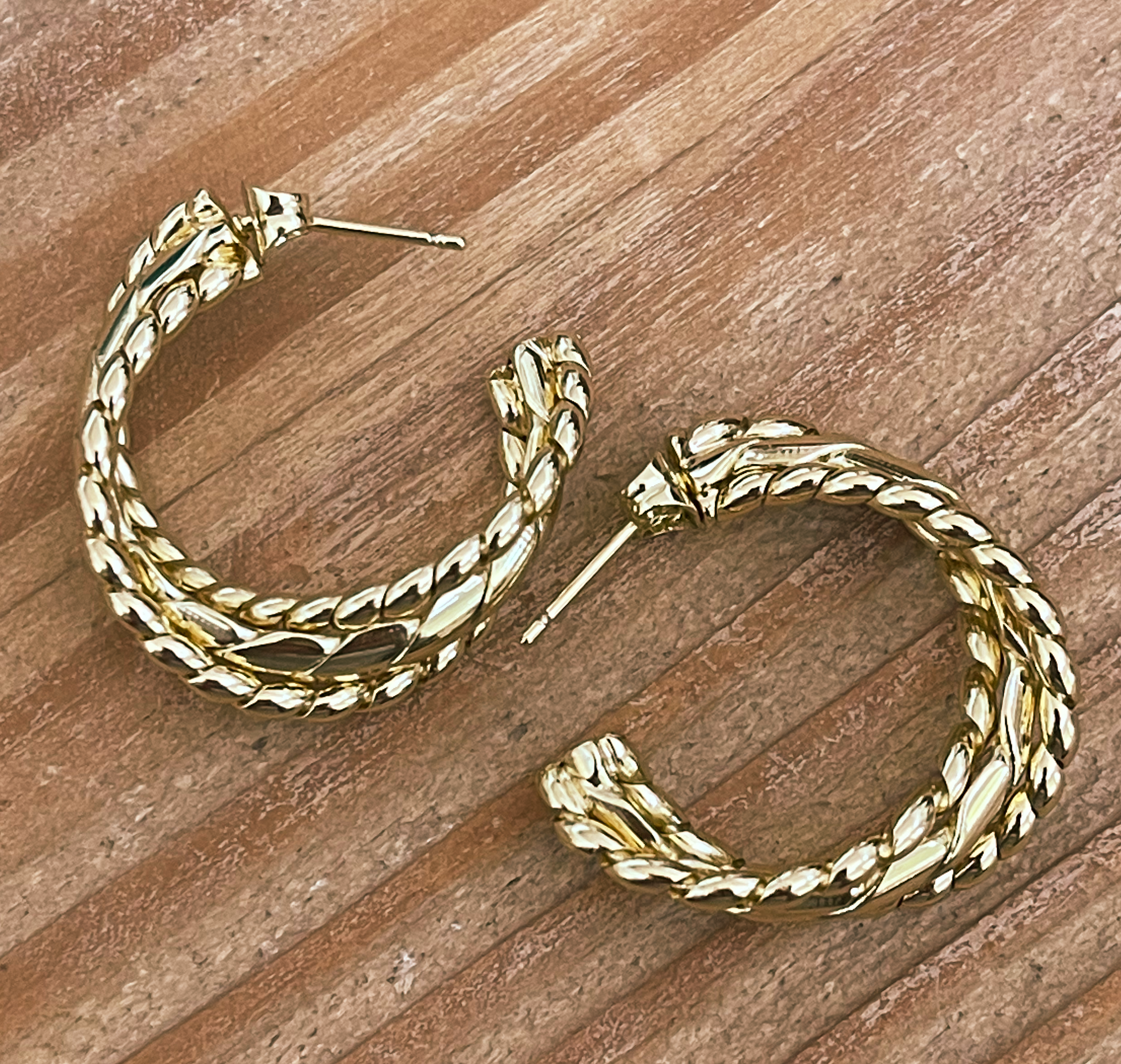 Gold hoop earrings on a wooden surface