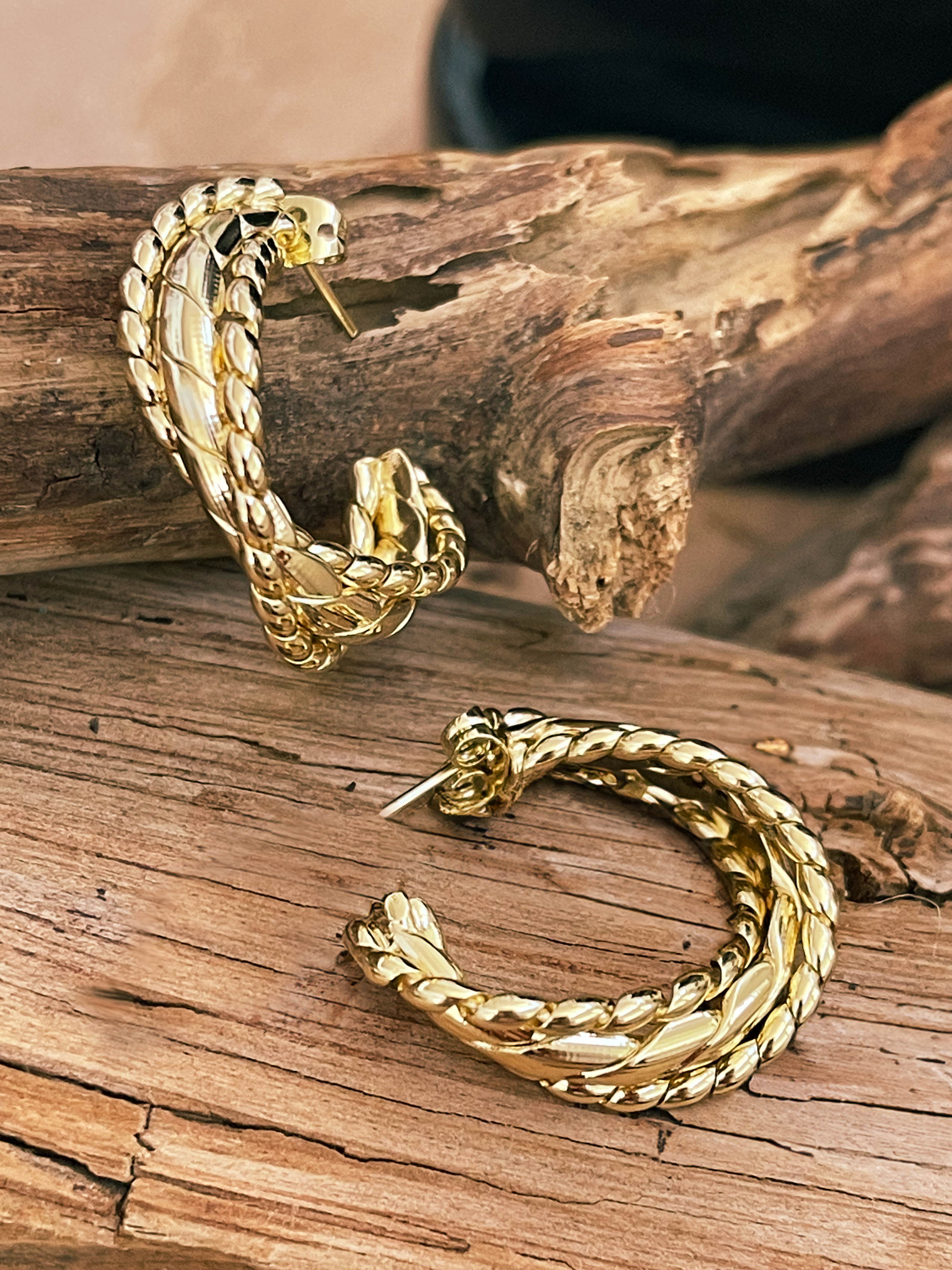 Gold hoop earrings on a wooden surface