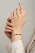 Gold bracelet on a wrist with a neutral background