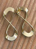 Gold infinity-shaped earrings on a wooden surface