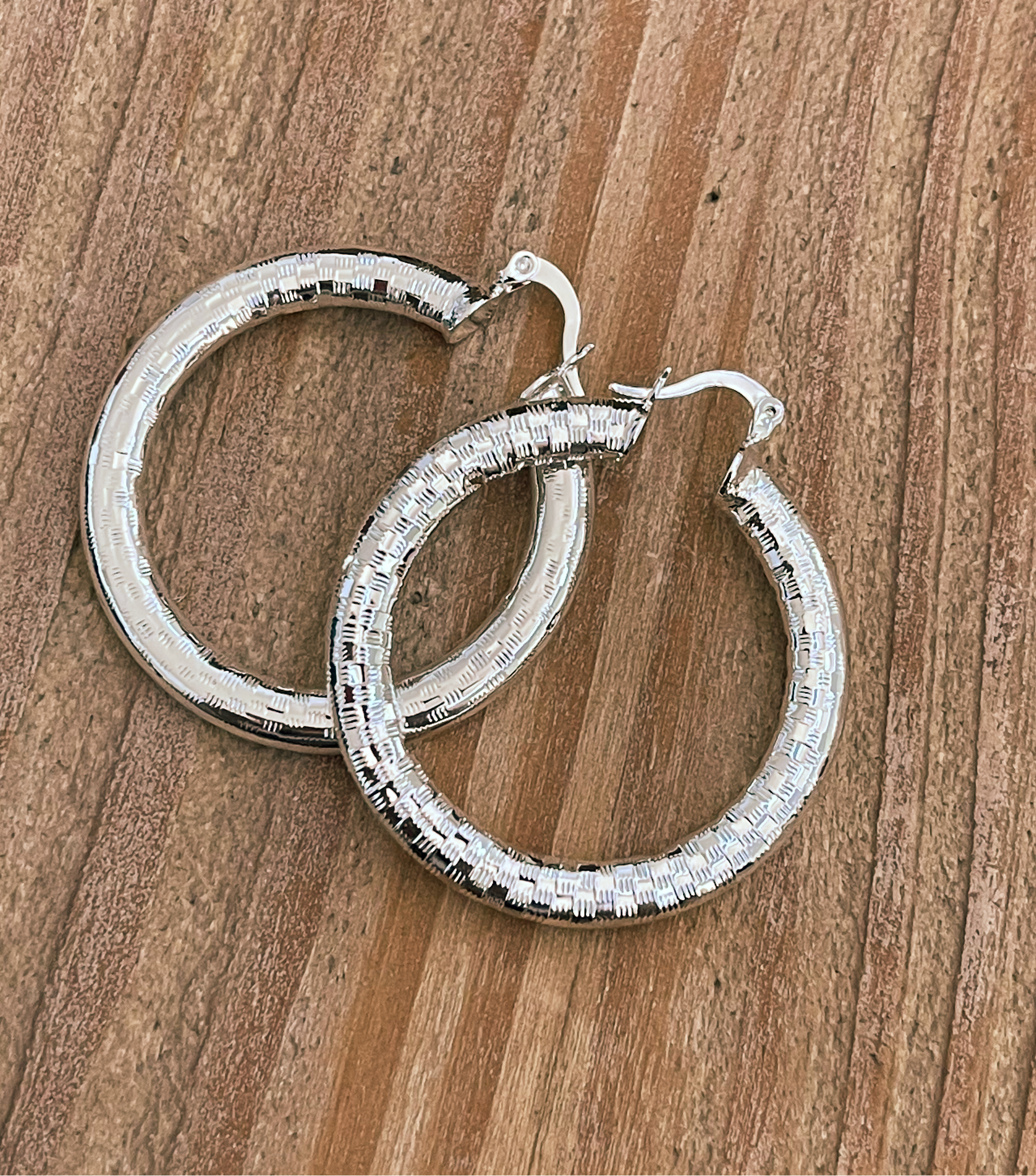 Silver hoop earrings on a wooden surface