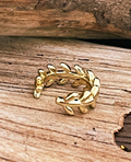 Gold ring with leaf design on a wooden surface
