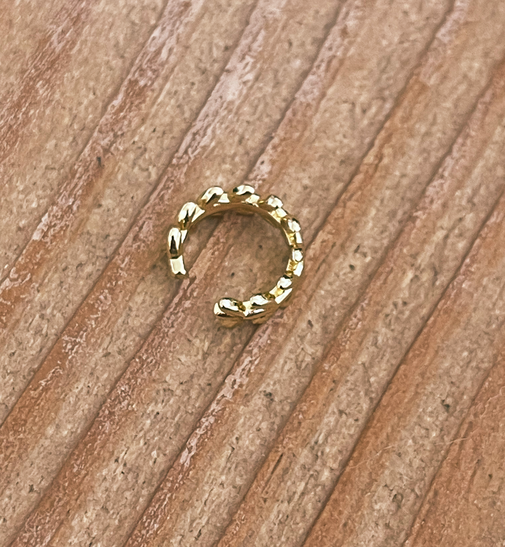 Gold hoop earring on a wooden surface