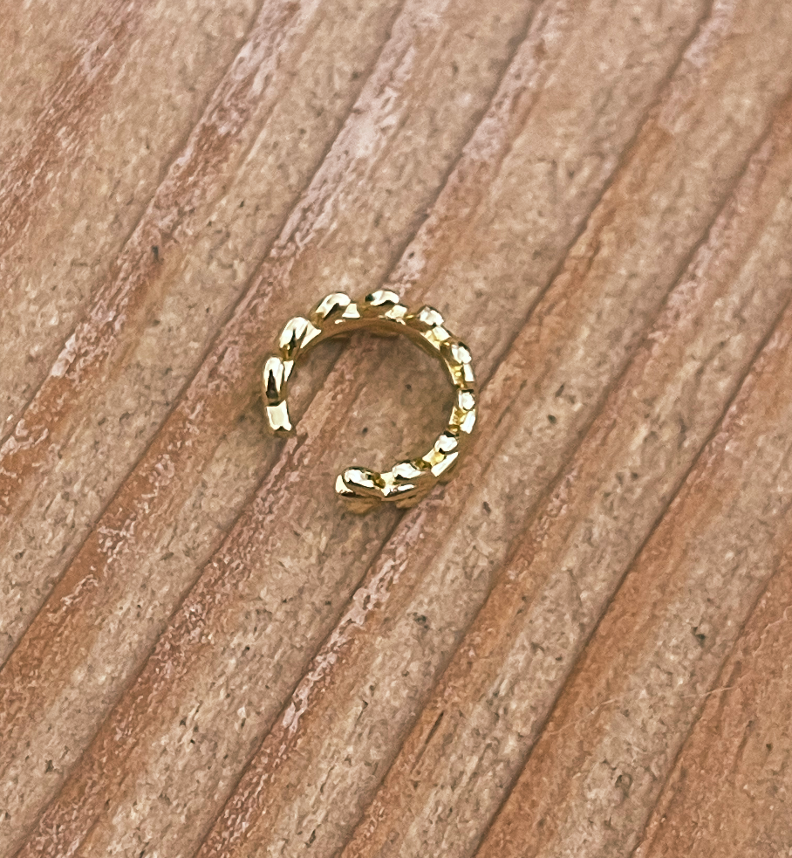 Gold hoop earring on a wooden surface