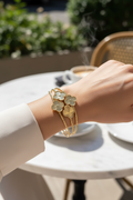 Gold bracelet on a wrist with a blurred outdoor background