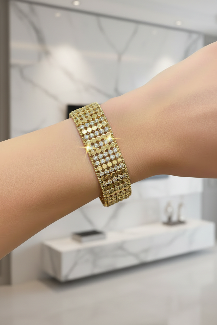 Gold bracelet on a wrist with a blurred indoor background