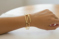 Gold bracelet on a wrist with a neutral background
