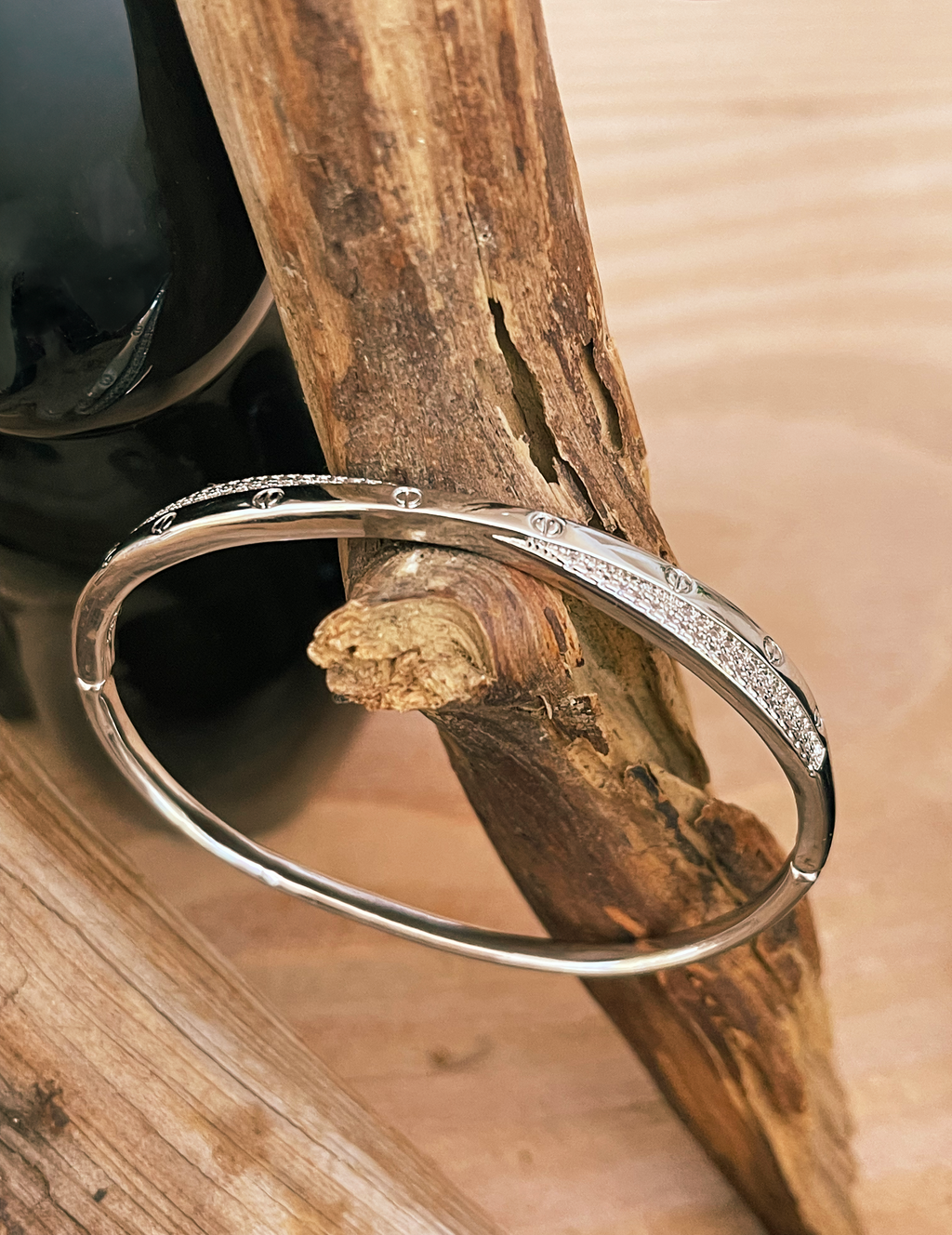 Silver bracelet on a wooden branch with a blurred natural background