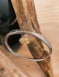 Silver bracelet on a wooden branch with a blurred natural background