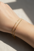 Gold bracelet on a person's wrist with a neutral background